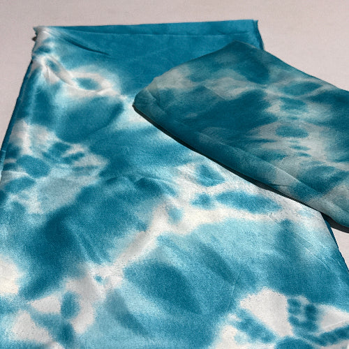 Blue and white tie-dye fabric on a light gray background