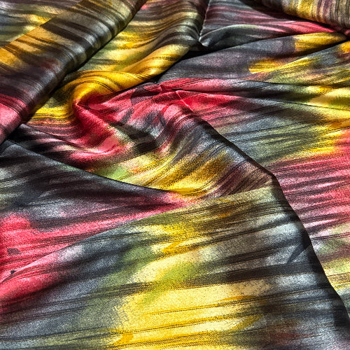 Multicolored fabric with a tie-dye pattern in shades of red, yellow, and black.