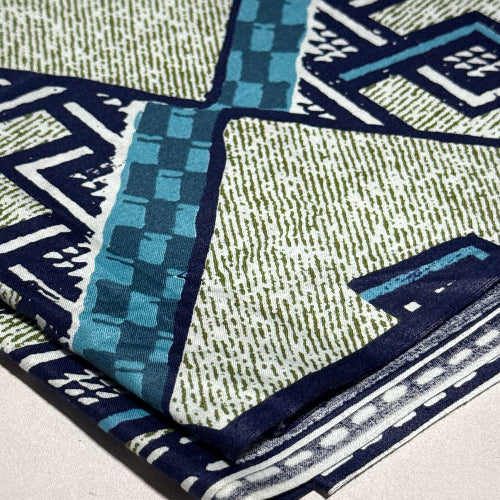 Close-up of patterned fabric with blue, green, and white design on a light background