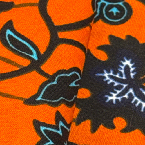 Close-up of a fabric with black and blue floral patterns on an orange background