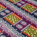 Patterned fabric with geometric designs in green, red, and purple on a white background