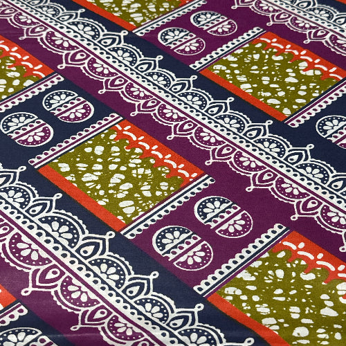 Patterned fabric with geometric designs in green, red, and purple on a white background