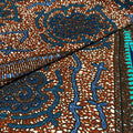 Close-up of a fabric with intricate blue and gold embroidery on a brown background
