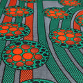 Patterned fabric with circular designs in orange, green, and black.