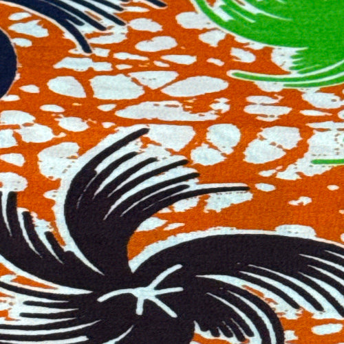 Close-up of a fabric with black bird design on an orange and white patterned background
