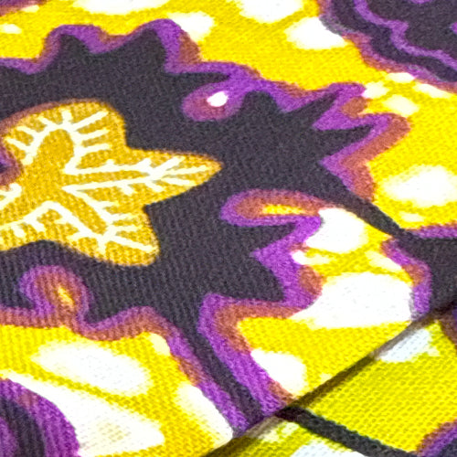 Close-up of a fabric with purple and gold abstract patterns on a yellow background