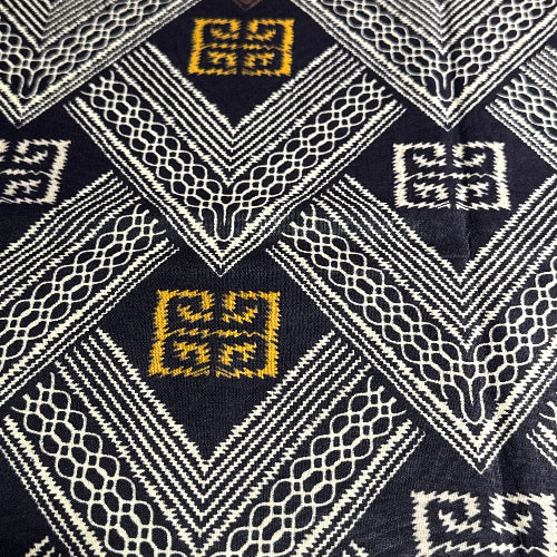 Close-up of a fabric with geometric patterns in black, white, and gold.