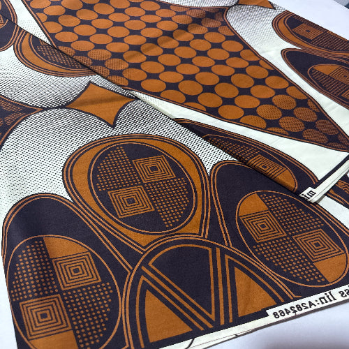 Close-up of a patterned fabric with brown and blue designs on a white background