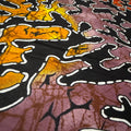 Close-up of a fabric with a batik pattern featuring black, orange, and purple colors.