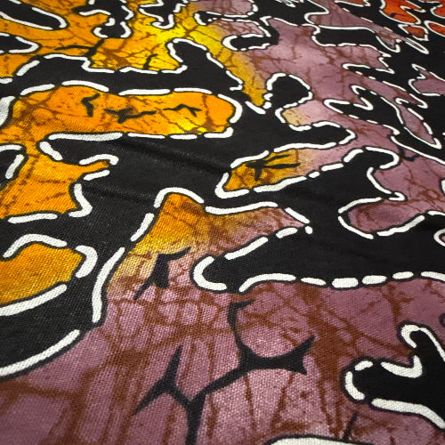 Close-up of a fabric with a batik pattern featuring black, orange, and purple colors.