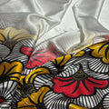 Close-up of fabric with a floral pattern in red, yellow, and black on a white background