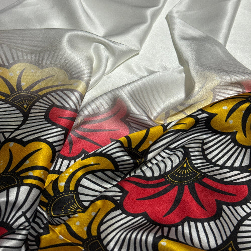 Close-up of fabric with a floral pattern in red, yellow, and black on a white background