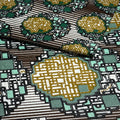 Close-up of a patterned fabric with geometric shapes in gold, green, and brown.