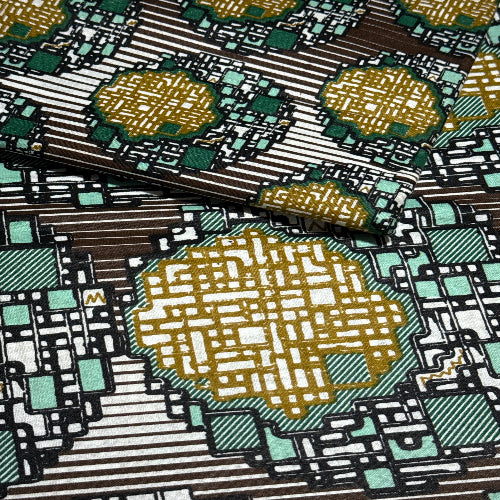 Close-up of a patterned fabric with geometric shapes in gold, green, and brown.