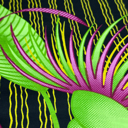 Close-up of colorful fabric with green, pink, and yellow patterns on a black background.