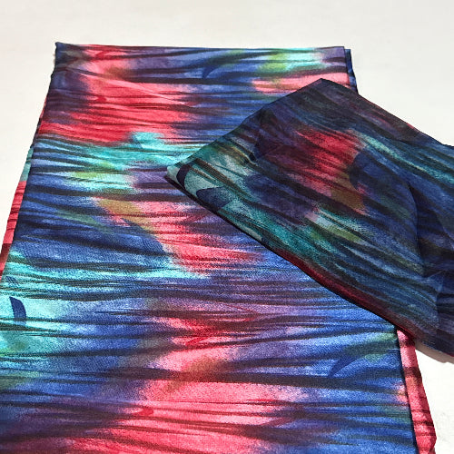 Colorful tie-dye fabric with a pattern of blue, red, and green on a white background.