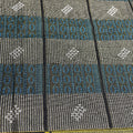 Close-up of a patterned fabric with geometric designs in gray, blue, and black.
