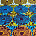 Patterned fabric with circular designs in blue, yellow, and brown on a white background