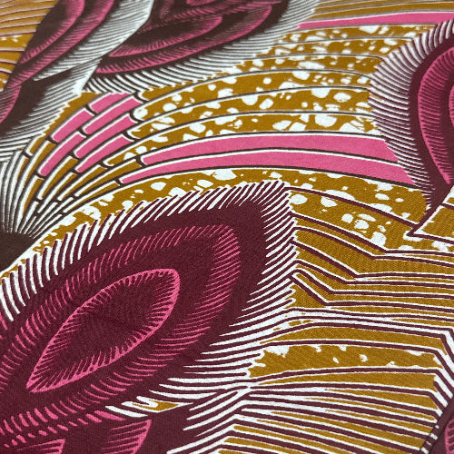 Close-up of a fabric with a pattern of pink, gold, and white shapes.