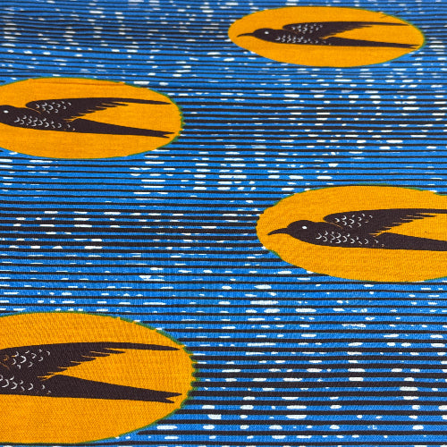 Patterned fabric with yellow circles and black abstract shapes on a blue and white striped background
