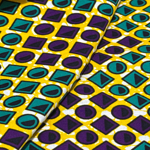 Colorful geometric patterned fabric with purple, green, and yellow shapes.