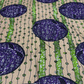 Patterned fabric with purple and green design on a beige background