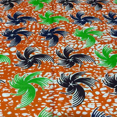 Patterned fabric with black, green, and white designs on an orange background