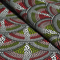 Textile with a pattern of dots and triangles in red, green, and white on a black background