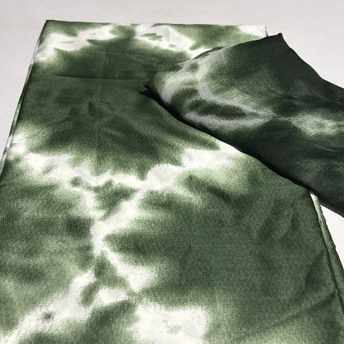 Green and black fabric with a tie-dye pattern on a white background