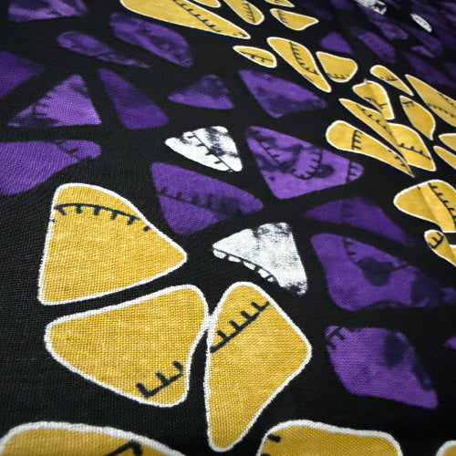 Close-up of fabric with yellow and purple abstract patterns on a black background