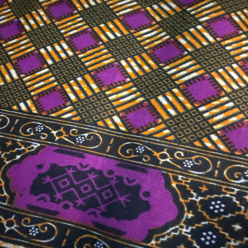 Close-up of a fabric with intricate patterns including geometric shapes and floral elements.