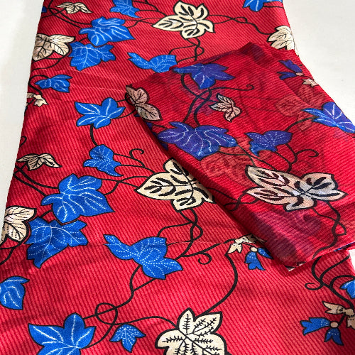 Red fabric with blue and beige floral patterns on a white background