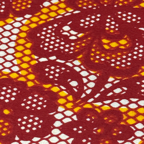 Close-up of a patterned fabric with red, yellow, and white colors.