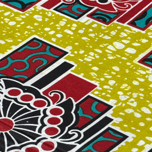 Close-up of a colorful fabric pattern with red, black, and green colors on a yellow background.