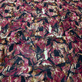 Close-up of a textured fabric with a leaf pattern in red, brown, and black.