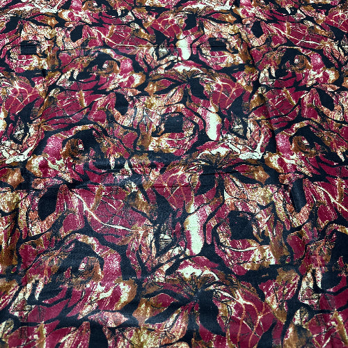 Close-up of a textured fabric with a leaf pattern in red, brown, and black.