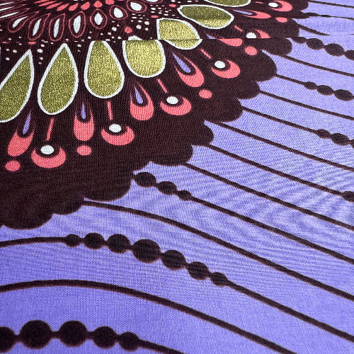 Close-up of a colorful fabric pattern with black, pink, green, and purple on a blue background.