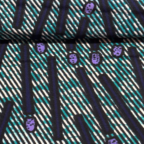 Close-up of a patterned fabric with diagonal lines and purple shapes.