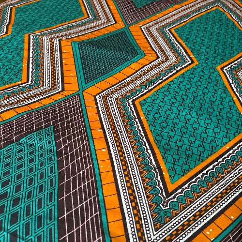 Close-up of a patterned fabric with geometric designs in green, orange, and black.