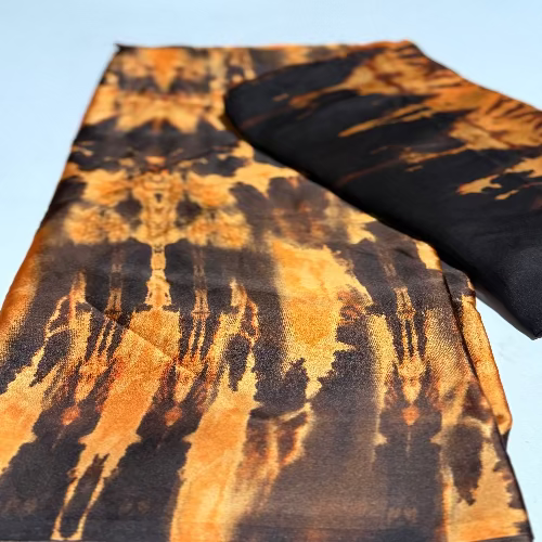 Tie-dye patterned fabric with orange and black colors on a light blue background