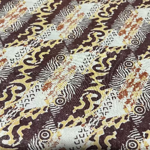 Close-up of a patterned fabric with swirls and circular designs in brown, yellow, and white.