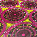 Close-up of fabric with pink and black circular pattern on a yellow background
