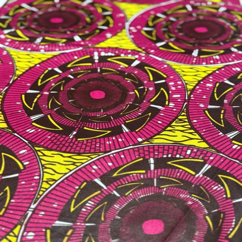 Close-up of fabric with pink and black circular pattern on a yellow background