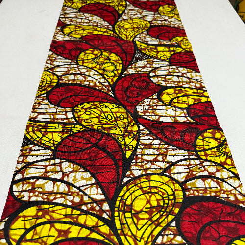 Decorative table runner with red and yellow leaf pattern on a white background
