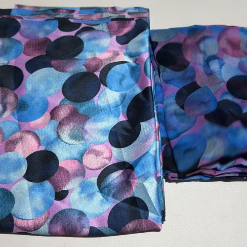 Two folded fabric pieces with a colorful polka dot pattern on a white background