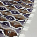 Close-up of patterned fabric with a visible label, featuring shades of purple, white, and brown.