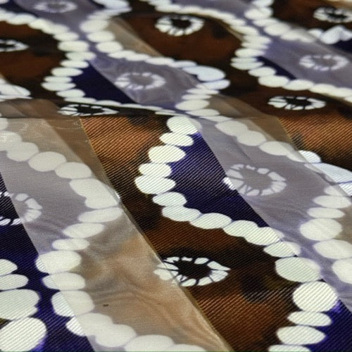 Close-up of patterned fabric with circular designs in brown, white, and blue.